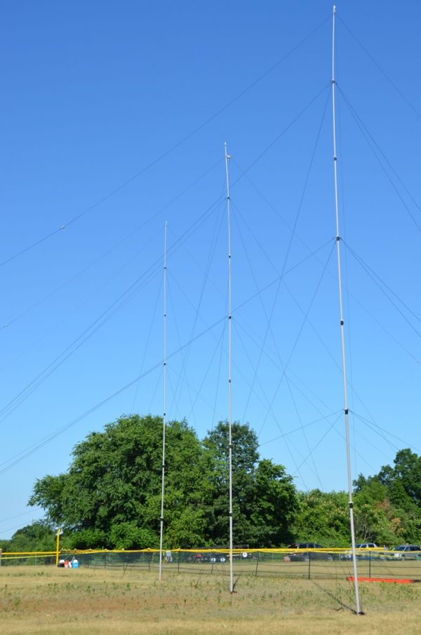 Three Masts setup with Ground Mounts in a field as supports for a mobile dipole antenna system